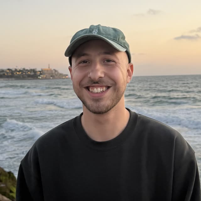 Alon Eijkenaar smiling on a rocky seawall at sunset